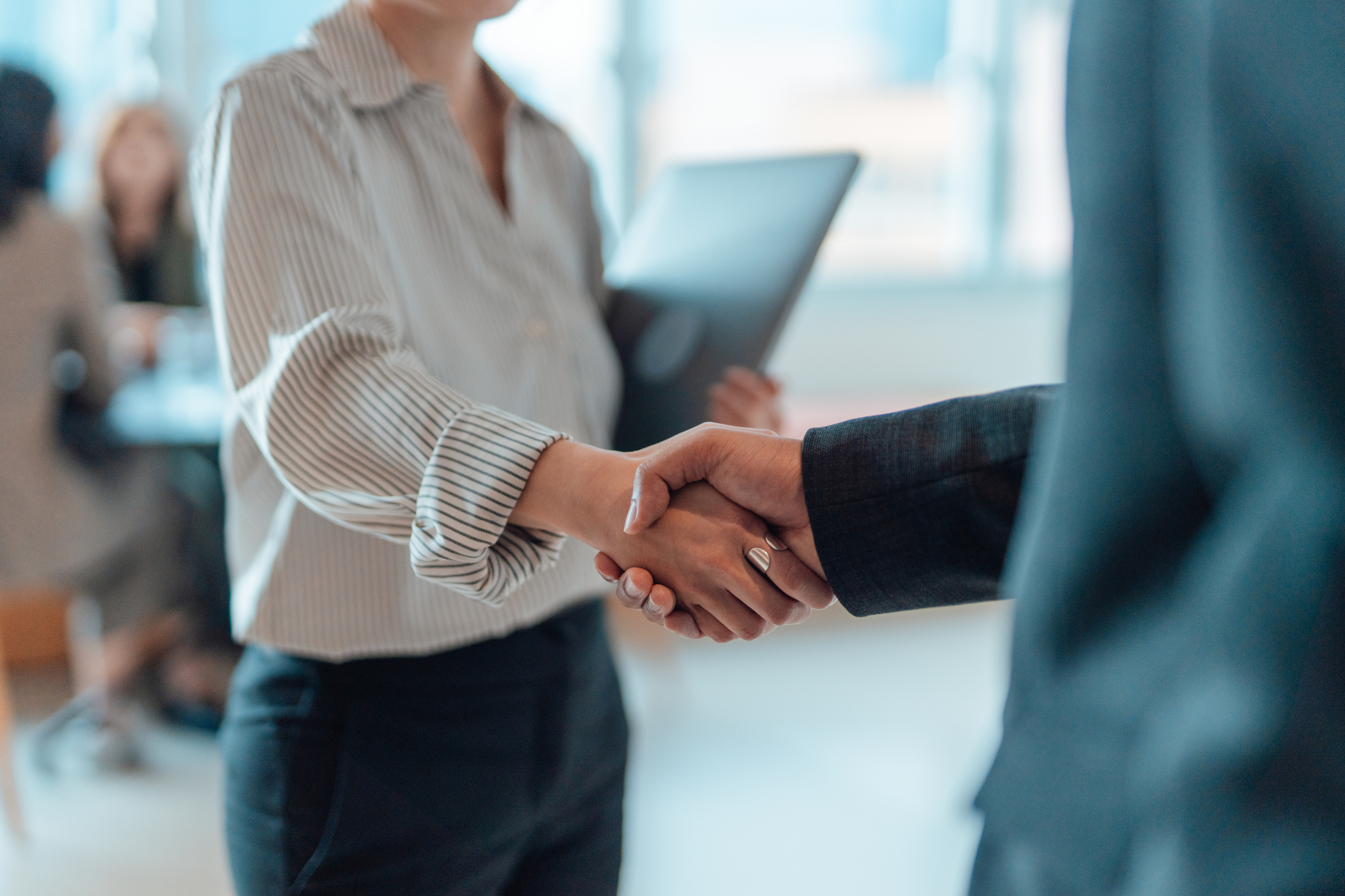 Hands shake, sealing a deal; business setting.